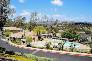 View of pool from hill overlooking street with mountains in distance