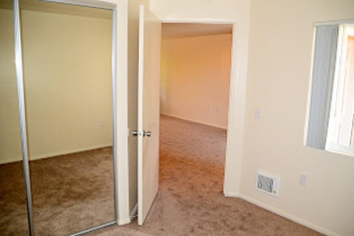carpeted bedroom facing closet with mirrored door and door facing living room