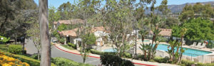 View of pool from hill overlooking street with mountains in distance